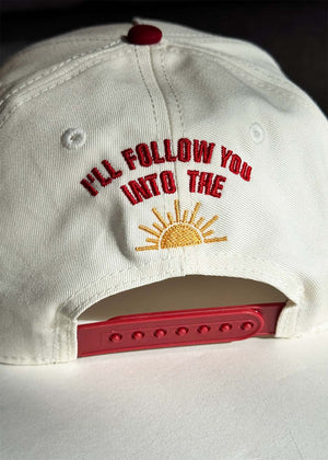 White cap with lyric and yellow sun embroidered at the back