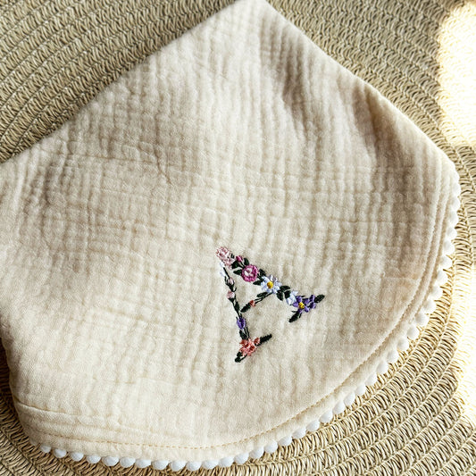 MUSLIN POM POM BIB: FLORAL MONOGRAM