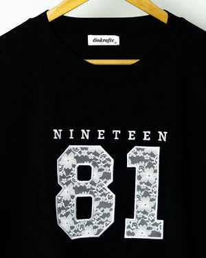 Black Martina Tee embroidered with Nineteen 81 in lace applique