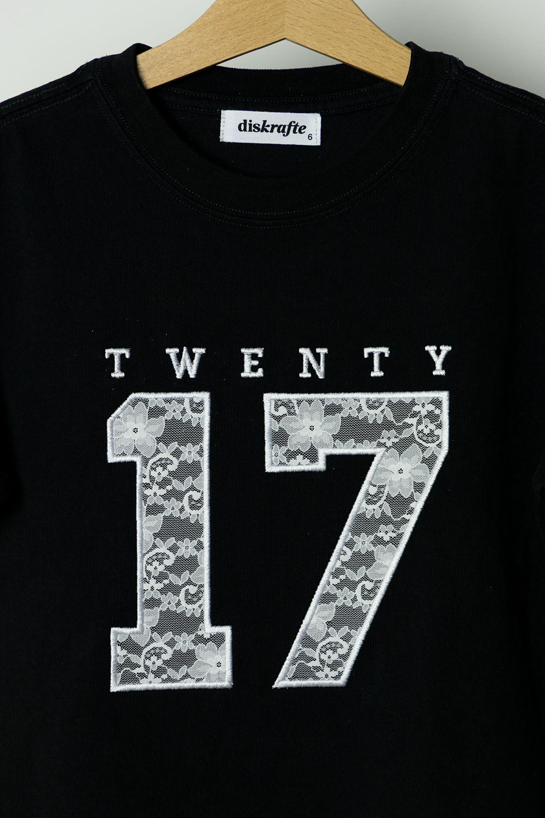 Black t-shirt with 'TWENTY 17' applique embroidered in white lace design 