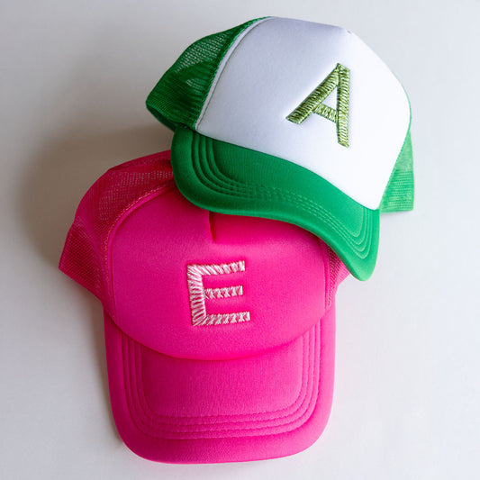 Pink and green trucker hat with 3D  weave letter 'E' and 'A' on a white background